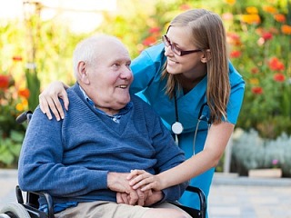 Symbolbild: Eine junge Pflegerin kümmert sich um einen älteren Herrn im Rollstuhl. Pflege wird wie auch Erziehungs- und Sorgearbeit in Deutschland weitgehend von Frauen geleistet.© stock.adobe.com 